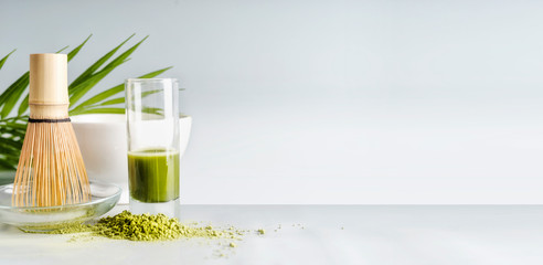 Matcha espresso in glass with whisk on table at light background, front view with copy space....