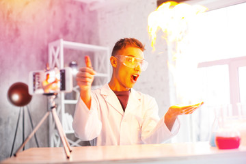 Emotional student wearing white coat making experiment with fire in laboratory
