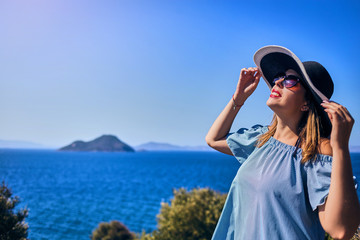 Fototapeta na wymiar Beautiful woman in beach hat enjoying sea view with blue sky at sunny day in Bodrum, Turkey. Vacation Outdoors Seascape Summer Travel Concept
