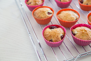 homemade cupcakes with cherry, muffins on a wire rack on a white table.