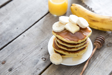 Sweet Homemade Stack of Pancakes with Butter, banan and Honey for Breakfast