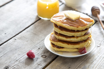 Sweet Homemade Stack of Pancakes with Butter, raspberryes and Honey for Breakfast