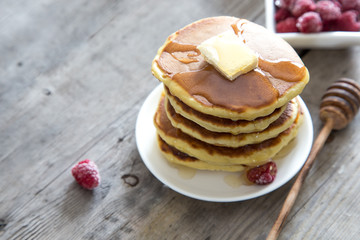 Sweet Homemade Stack of Pancakes with Butter, raspberryes and Honey for Breakfast