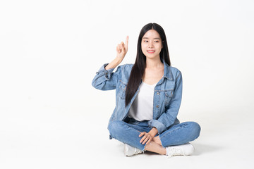 Thinking asian woman sitting on floor isolated on white background.Asian female model smiling looking up.woman pointing fingers away while sitting on a floor with legs crossed isolated