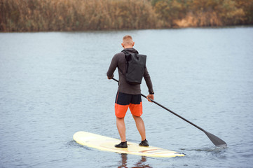 Adult man standing with paddle on paddleboard © serguastock
