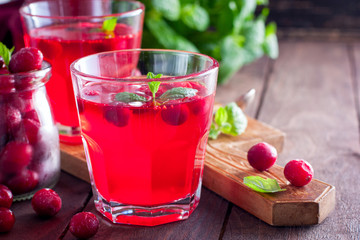Refreshing vitamin drink from frozen cranberries in glass cups on a wooden table, copy space, horizontal