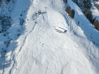 Obraz premium Aerial view of cottage in snow. Remote building with snow covered roof in Switzerland.