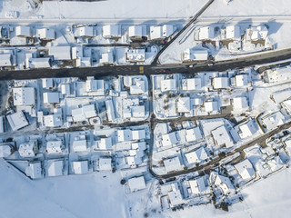 Aerial view of town with snow covered houses. Roof tops with snow on residential buildings in...