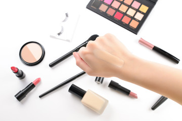 Foundation in woman hands. Professional makeup products with cosmetic beauty products, foundation, lipstick,  eye shadows, eye lashes, brushes and tools.