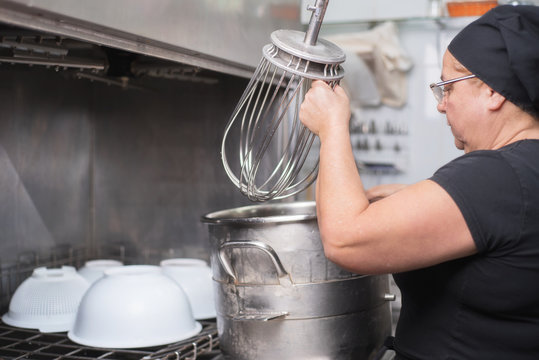 Woman Employee Loading Casseroles Into An Industrial Dishwasher In The Restaurant .