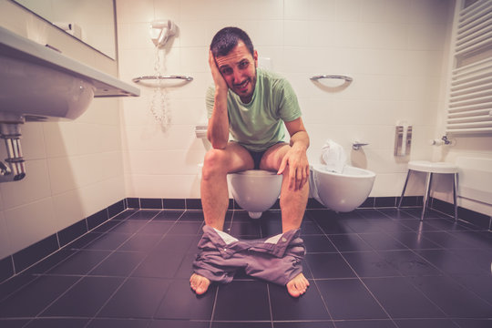 Young man suffering from diarrhea sit on toilet bowl at home