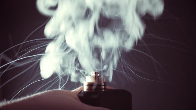 Steam when using vape device, RDA atomizer without top cap, low Ohm clapton coils and vapour from e-liquid, close up