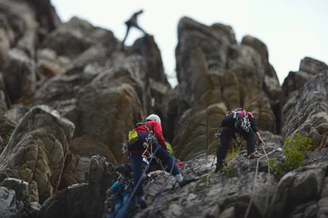 Foto auf Alu-Dibond  A group of climbers are on a self-insurance against the background of high rock towers. Tilt-Shift effect. © esalienko