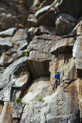  The climber descends the rope on the background of a huge rock wall. Tilt-Shift effect.