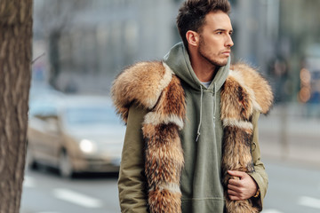 Fashionable man walk outdoors wear  fur jacket with street background - Image