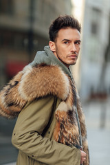 Fashionable man walk outdoors wear  fur jacket with street background - Image