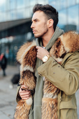 Fashionable man walk outdoors wear  fur jacket with street background - Image