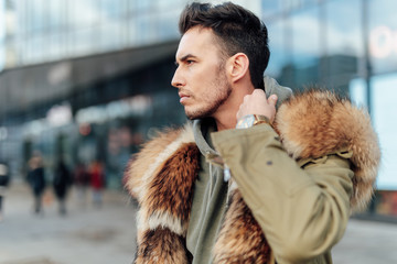 Fashionable man walk outdoors wear  fur jacket with street background - Image