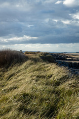 the normandy beaches in france showing ruins and relics from world war II on golden sands and dark...