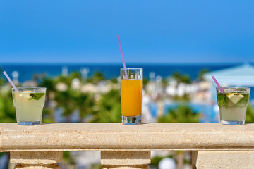Three glasses with cocktails against the picturesque hotel’s view, illustrating the great family holidays.