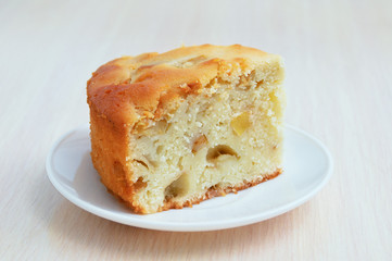 Sliced piece of cake on a white plate. On the wooden kitchen table.