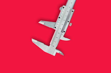 One metal vernier caliper on red table with copy space for your text. Top view. Industrial concept