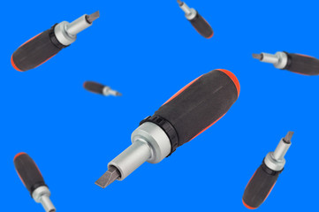 Lot of falling ratchet screwdriver with orange and black plastic with rubber handle and bit on blue background