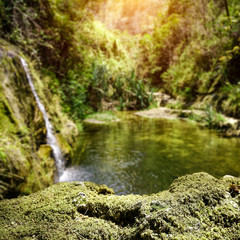 Naklejka na ściany i meble Exotic waterfall background with green moss space for your product. Summer time on Madagascar 