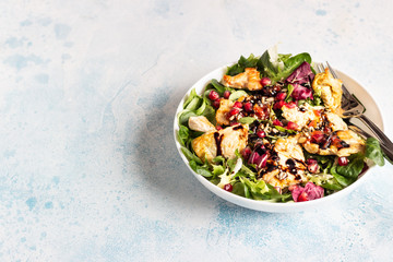 Salad mix with grilled turkey or chicken, seeds and citrus dressing on a white plate. Light concrete background. Healthy lunch or dinner. Copy space.