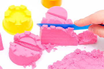Hands of a kid playing with pink magic sand.