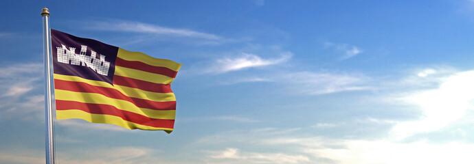Bandera de las Islas Baleares subida ondeando al viento con cielo de fondo