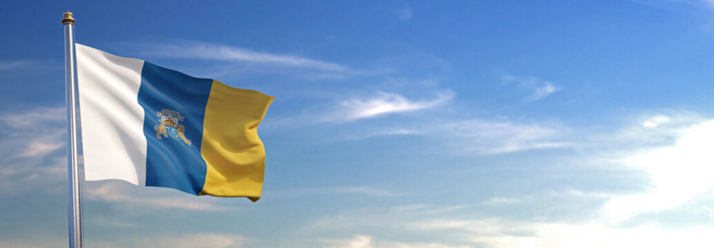 Bandera de las Islas Canarias subida ondeando al viento con cielo de fondo