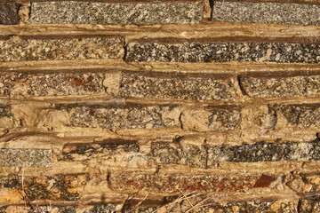Fragment of a wall of small granite blocks. On the wall a thin layer of water flows. Background