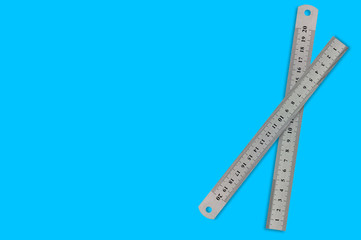 Pair of metal straightedges with digits and scale on blue background with copy space for your text