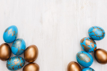 golden decorated easter eggs on white wooden background