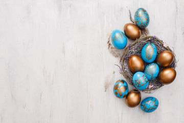 golden decorated easter eggs on white wooden background