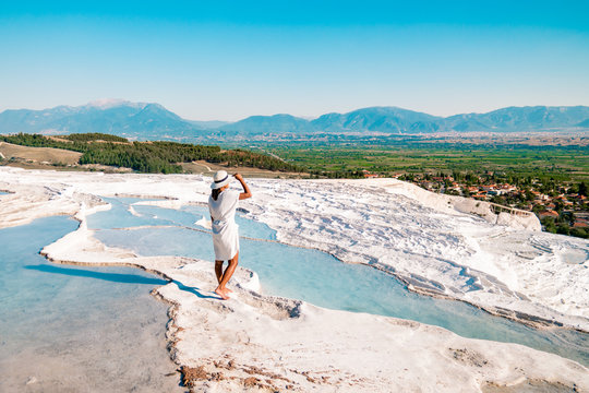 Natural travertine pools and terraces in Pamukkale. Cotton castle in southwestern Turkey, girl in white dress with hat natural pool Pamukkale