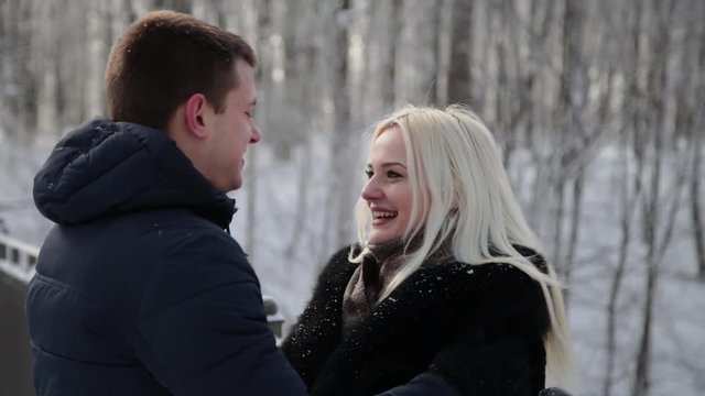 Beautiful young couple hugging and talking in a city winter park.