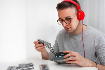 Mężczyzna naprawia kasetę magnetofonową. - obrazy, fototapety, plakaty