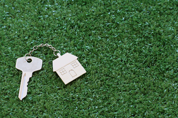 Home key with house keyring on white wood table background, property concept
