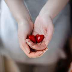 Young woman holding in hands two red hearts on gray background.Valentine Day concept.