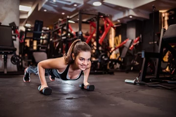Gardinen Beautiful smiling girl doing push-up on weights. © bnenin