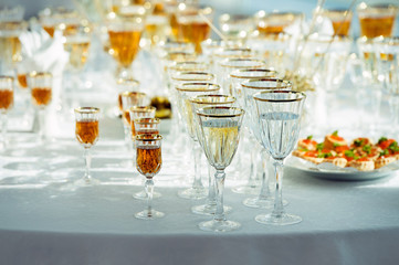 A lot of glasses with champagne, vermouth and whiskey on the table