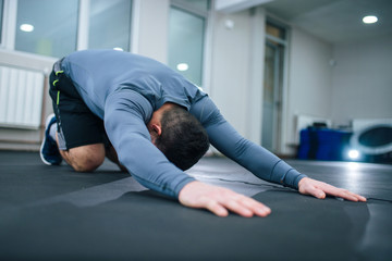 Low angle image of muscular man stretching back indoors.