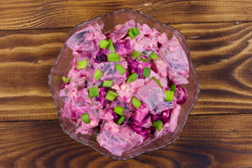 Tasty salad with herring, beetroot, eggs, onion and mayonnaise on wooden table. Top view