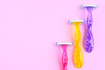 Set of three woman colorful razors with selective focus on pink background. New disposable plastic razor with steel blade for daily safety personal shaving with empty space for text.