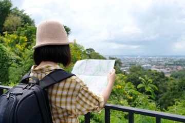 Young asian girl traveler standing with backpack and map while traveling in countryside outdoor, people spring and summer holiday vacation background concept