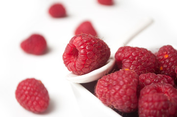 Closeup of raspberries in a white bowl on white background