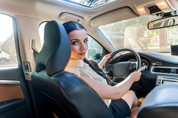 Beautiful woman inside car holding steering wheel