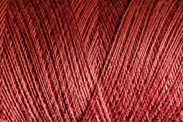 The red cotton thread is tightly wound on a bobbin. Background image.